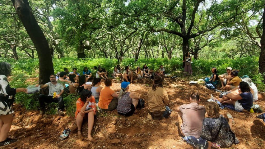 Grupo de pessoas sentadas no chão em círculo no campo